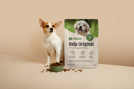 Hunden Doris poserar bredvid en påse FirstVet Valp